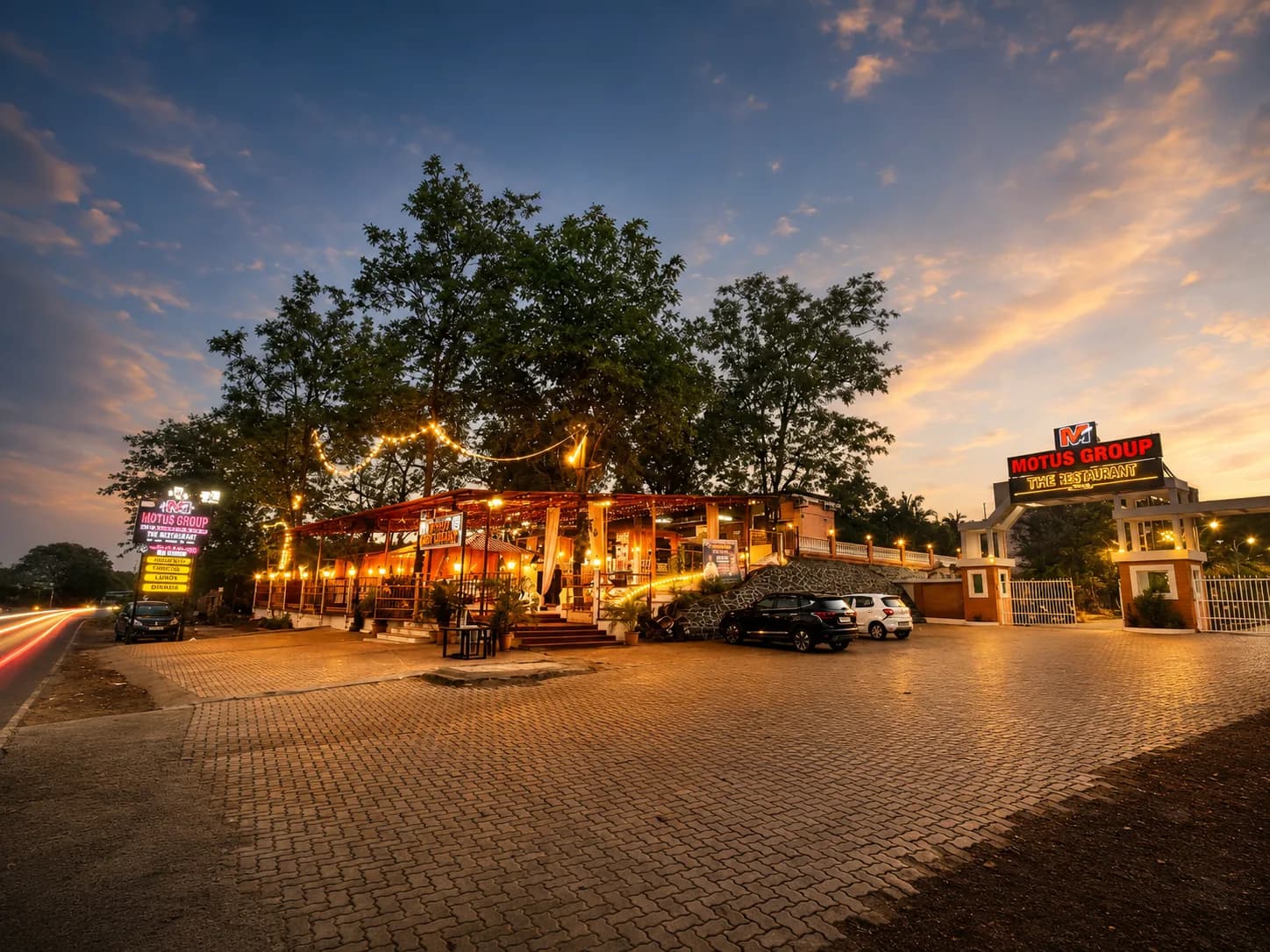 Motus Group restaurant at dusk, with string lights over the pavilion and the gated entrance